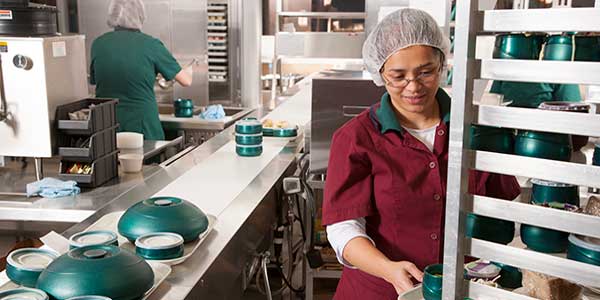 Female worker in hospital kitchen preparing patient meals
